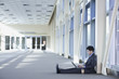 Chinese businessman sitting on floor of lobby using laptop