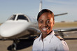 African American pilot standing near private jet