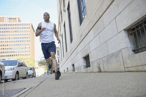 Photo: African American man running on city sidewalk African American man running on city sidewalk