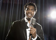 Smiling Black man in tuxedo standing at microphone