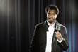 Smiling Black man in tuxedo standing at microphone