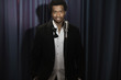 Smiling Black man in tuxedo standing at microphone