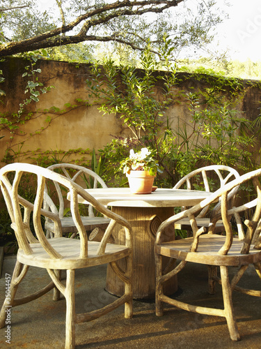 Foto: Empty chairs around a table in outdoor patio surrounded by lush foliage Empty chairs around a table in outdoor patio surrounded by lush foliage