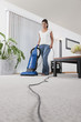 Hispanic woman vacuuming living room floor