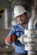 Hispanic worker turning valve on pipe