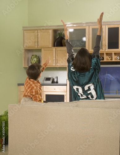 Photo: Mother and son cheering at football game on television Mother and son cheering at football game on television