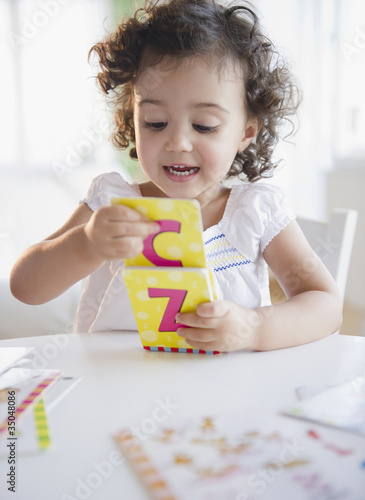 Photo: Mixed race girl playing with alphabet cards Mixed race girl playing with alphabet cards