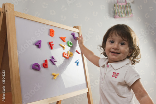 Foto: Hispanic baby playing with letters on magnetic board Hispanic baby playing with letters on magnetic board