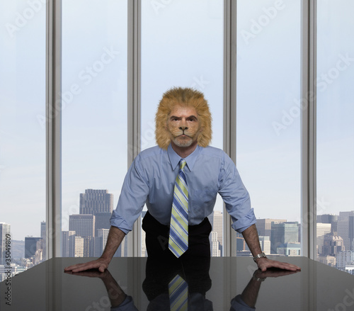 Photo: Businessman with lion's head leaning on table Businessman with lion's head leaning on table
