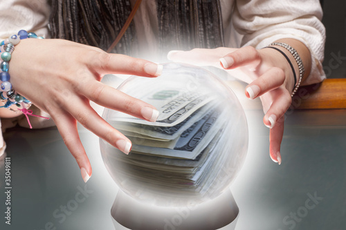 Photo: Mixed race fortune teller with crystal ball with money inside Mixed race fortune teller with crystal ball with money inside