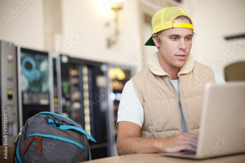 Photo: Caucasian man using laptop in train station Caucasian man using laptop in train station