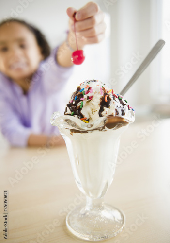 Photo: African American girl putting cherry ice cream sundae African American girl putting cherry ice cream sundae