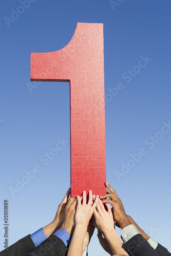 Photo: Business people lifting large number 1 Business people lifting large number 1