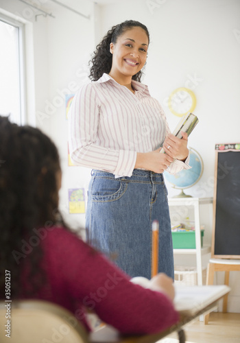 Photo: Mixed race teacher smiling in classroom Mixed race teacher smiling in classroom
