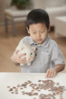 Korean boy putting coins in piggy bank