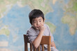 Korean boy sitting in chair near map