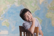 Korean boy sitting in chair near map