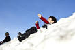 Mixed race boy sledding downhill in snow