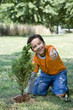 Hispanic boy planting tree and giving thumbs up