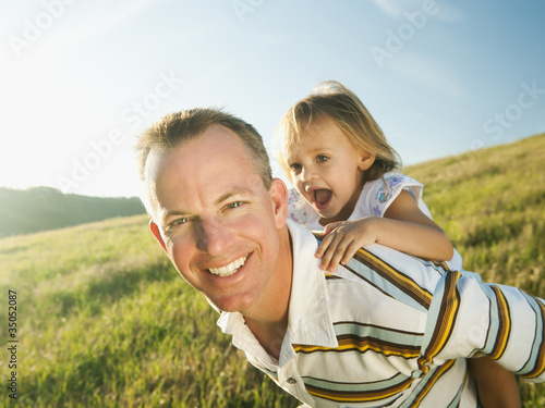 Foto: Father carrying daughter on his back in field Father carrying daughter on his back in field