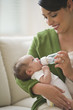 Hispanic mother feeding newborn baby girl