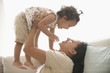 Hispanic mother playing with daughter on sofa
