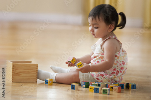 Foto: Hispanic girl sitting on floor playing with alphabet blocks Hispanic girl sitting on floor playing with alphabet blocks