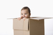 Mixed race baby boy playing in cardboard box