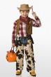 Caucasian boy in cowboy costume carrying jack o'lantern