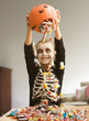 Caucasian boy in skeleton dumping out Halloween candy