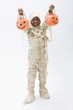 Black boy in mummy costume holding jack o'lanterns