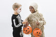 Boys in skeleton and mummy costumes trading Halloween candy