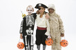 "Boys in skeleton, pirate and mummy costumes holding jack o'lantern"
