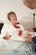 Senior Hispanic man bringing wife breakfast in bed