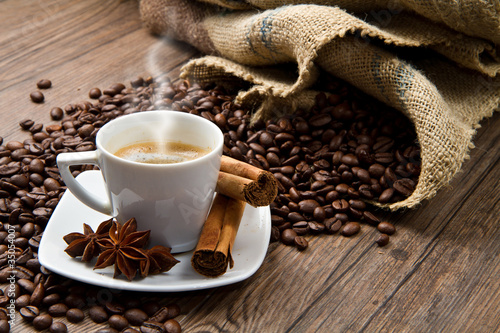 Foto: Coffee cup with burlap sack of roasted beans on rustic table Coffee cup with burlap sack of roasted beans on rustic table