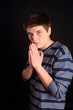 A young boy with his hands together o