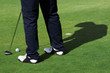 A man is standing on the green of a golf course.