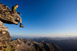 Photo: Young man sitting on rock above mountain range Young man sitting on rock above mountain range