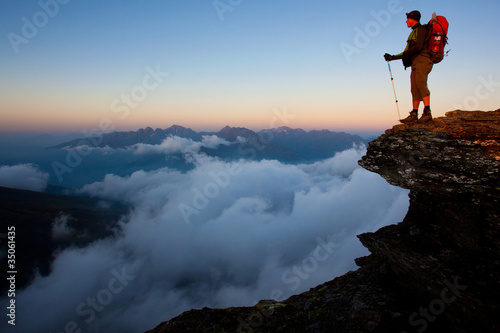Photo: Man with backpack high above the misty mountain valley Man with backpack high above the misty mountain valley