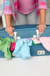 Teenage girl struggling to close suitcase