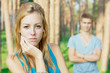 Upset young girl with a boy at the background