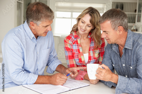 Photo: Mid age couple with financial advisor at home Mid age couple with financial advisor at home