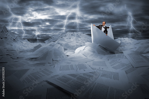 Foto: Businessman sailing in stormy papers sea Businessman sailing in stormy papers sea
