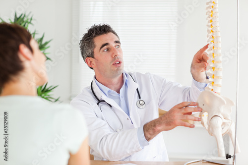 Photo: Doctor showing a woman a part of a spine Doctor showing a woman a part of a spine