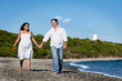 Photo: Pregnant woman walking ont he beach with husband Pregnant woman walking ont he beach with husband