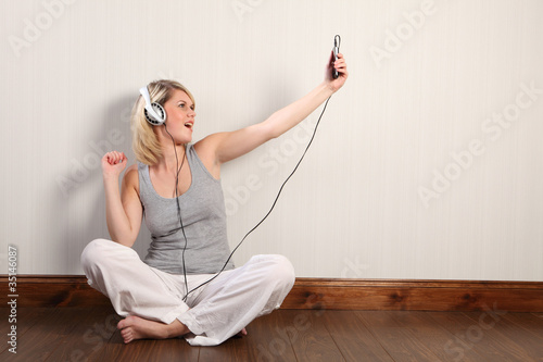 Photo: Beautiful blonde girl singing to music at home Beautiful blonde girl singing to music at home