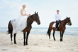 Beach wedding: bride and groom on a horses by the sea