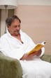 Old man in armchair reading a book