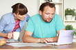 Happy couple calculating their bills by the table at home