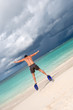 Tanned man jump in blue flippers on sand beach and ocean Tanned man jump in blue flippers on sand beach and ocean
